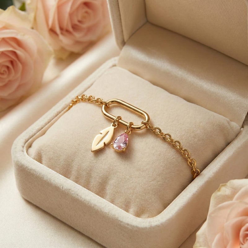 This attractive gold bracelet, crafted from rust-resistant stainless steel, features a modern link ring from which a delicate feather and a sparkling pink stone dangle. It has an adjustable clasp for a perfect fit. - Image 4